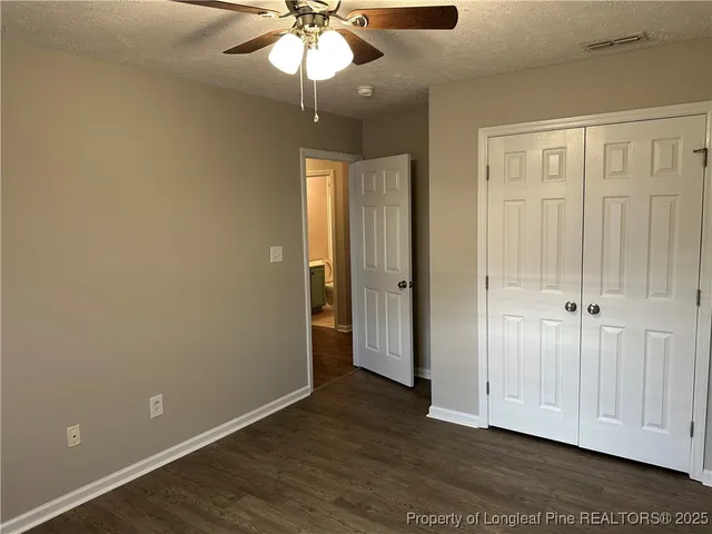 an empty room with wooden floor chandelier fan and windows