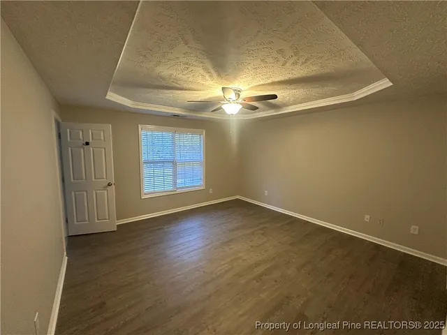 an empty room with wooden floor and a ceiling fan