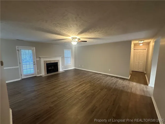 an empty room with wooden floor fireplace and windows
