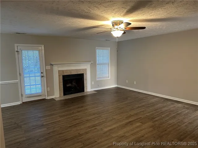 a view of an empty room with wooden floor fireplace and a window