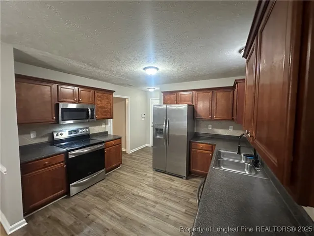 a kitchen with stainless steel appliances granite countertop a refrigerator stove and sink
