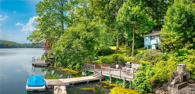 a view of a house with brick walls and a yard with plants and large trees