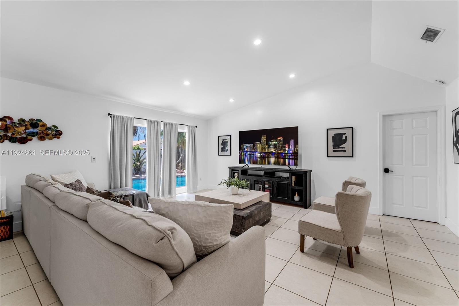 10020 Southwest 145th Place Miami, FL 33186 - Photo 31 of 35 a living room with furniture a flat screen tv and a refrigerator