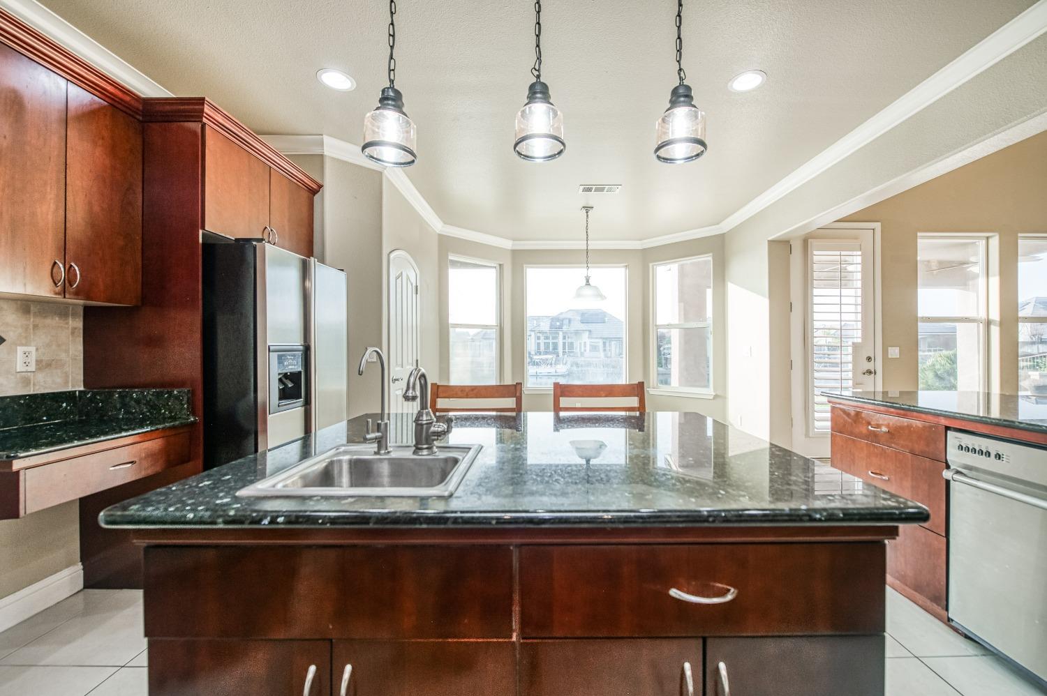 4679 North Island View Clovis, CA 93619 - Photo 9 of 55 a kitchen with kitchen island granite countertop a large window cabinets and stainless steel appliances
