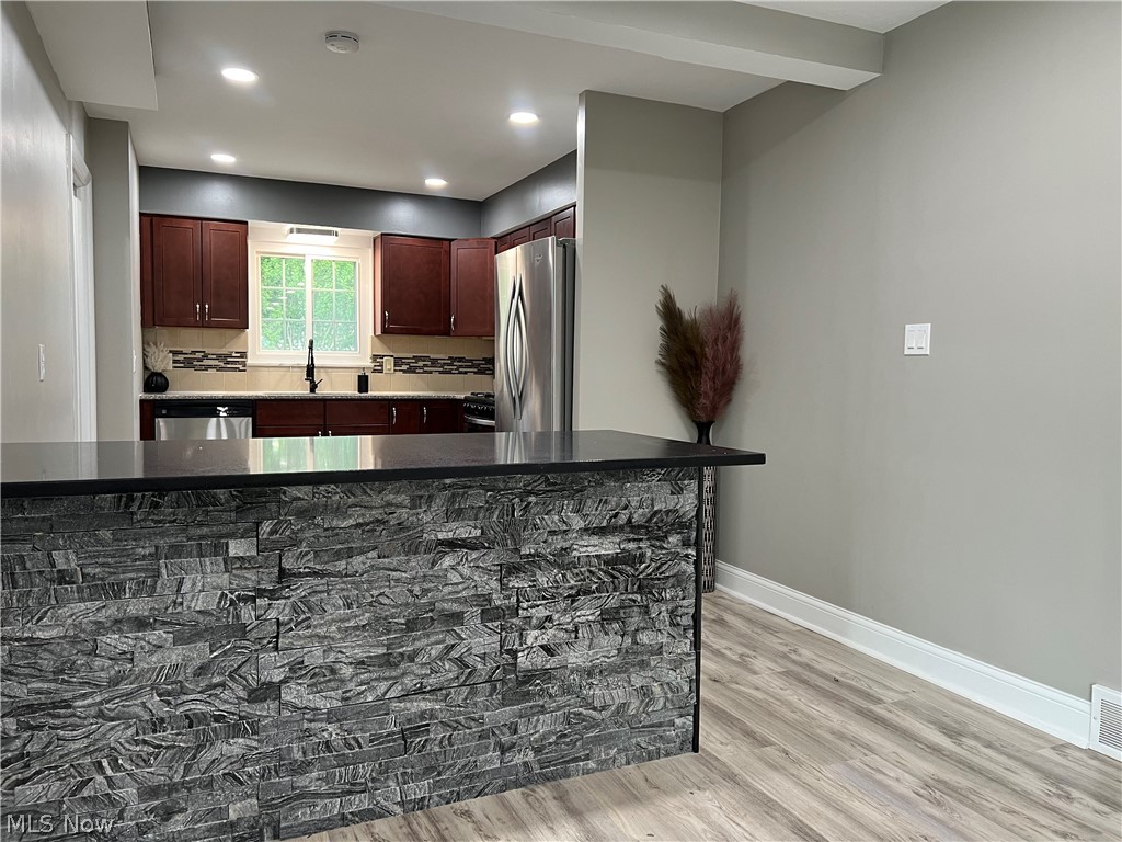 7475 Selwick Drive Parma, OH 44129 - Photo 6 of 29 Kitchen featuring dark stone counters, stainless steel appliances, tasteful backsplash, light wood-type flooring, and sink
