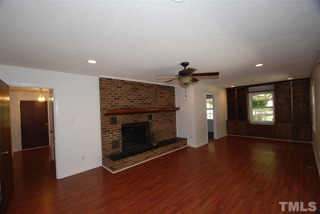 6908 Lake Wheeler Road Raleigh, NC 27603 - Photo 10 of 25 an empty room with wooden floor fireplace and windows