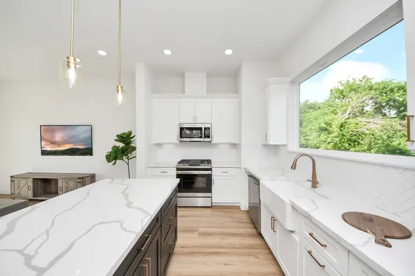 a large kitchen with kitchen island white cabinets and stainless steel appliances