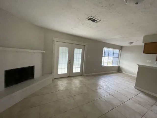 a view of an empty room with a window and fireplace
