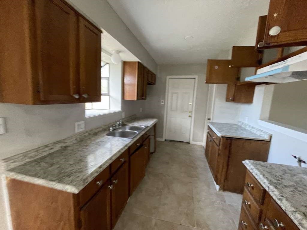 2310 Heather Street Highlands, TX 77562 - Photo 5 of 16 a kitchen with granite countertop a sink a stove and a wooden cabinets