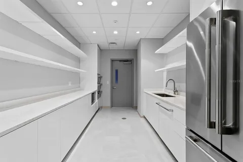 a large white kitchen with a refrigerator a sink and dishwasher