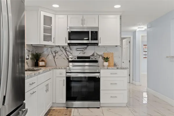 a large kitchen with stainless steel appliances kitchen island granite countertop a refrigerator and a sink
