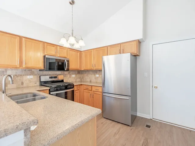 a kitchen with granite countertop a refrigerator oven a sink dishwasher and wooden floor