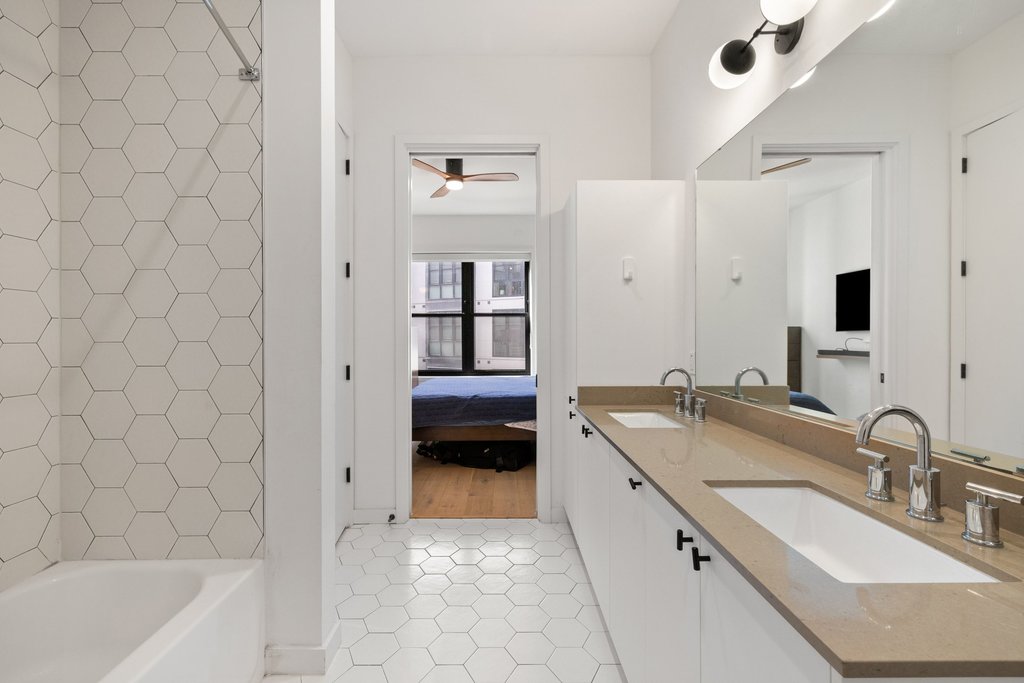 800 Embassy Drive, Unit 413 Austin, TX 78702 - Photo 13 of 27 Full bath featuring double vanity, connected bathroom, and light tile patterned floors