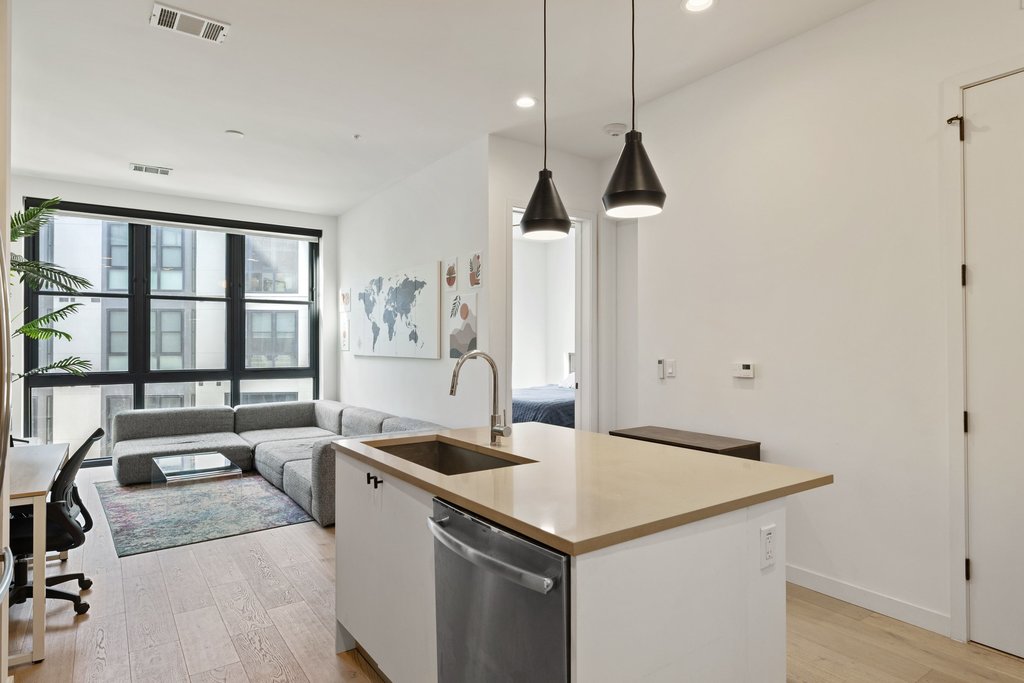 800 Embassy Drive, Unit 413 Austin, TX 78702 - Photo 7 of 27 Kitchen with an island with sink, light wood-style floors, decorative light fixtures, and stainless steel dishwasher
