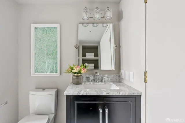 a bathroom with a granite countertop sink a toilet and a mirror