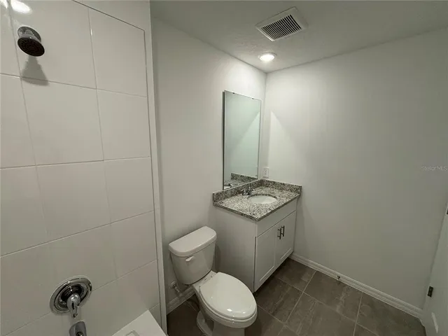 a bathroom with a granite countertop sink a toilet and shower