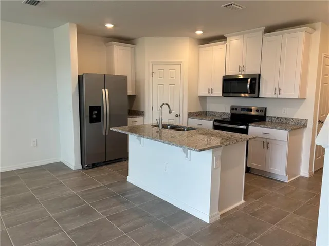 a kitchen with stainless steel appliances granite countertop a refrigerator and a stove top oven