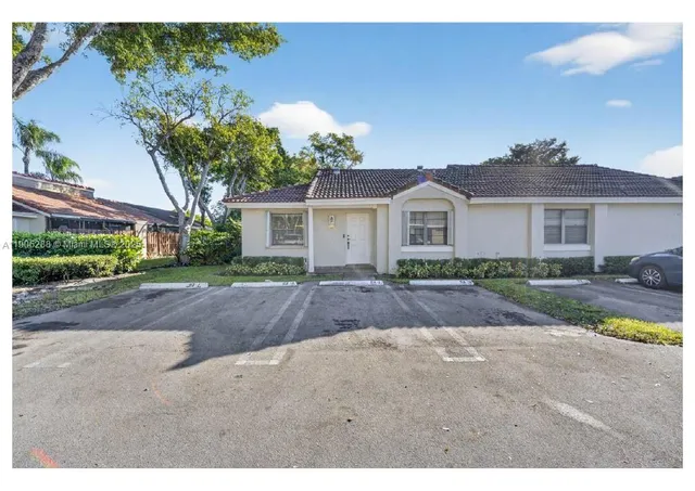 a front view of a house with a yard and potted plants