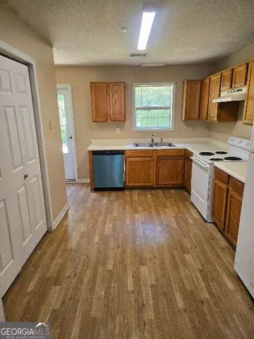 a kitchen with stainless steel appliances wooden floors and a stove