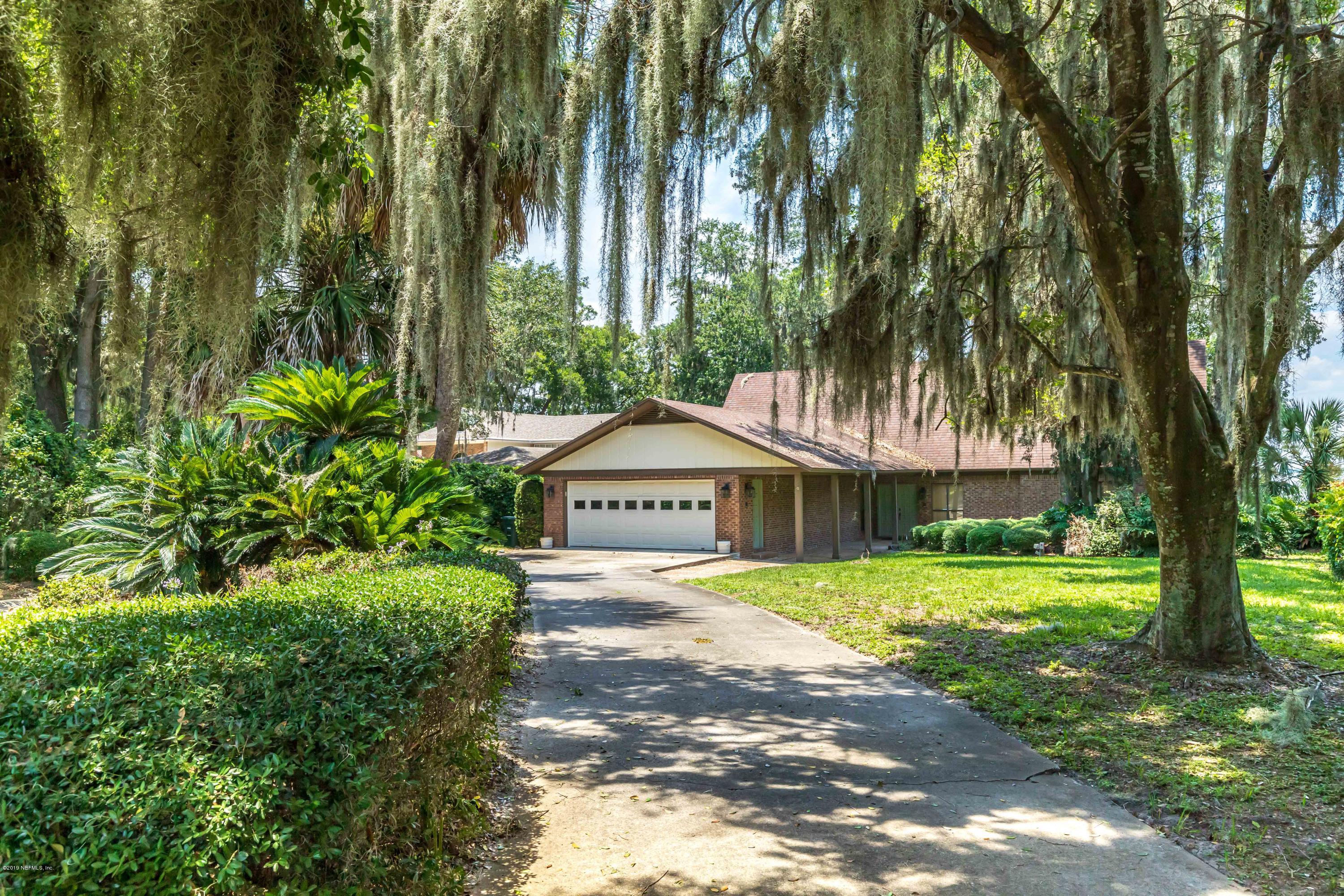a front view of a house with a yard and large trees