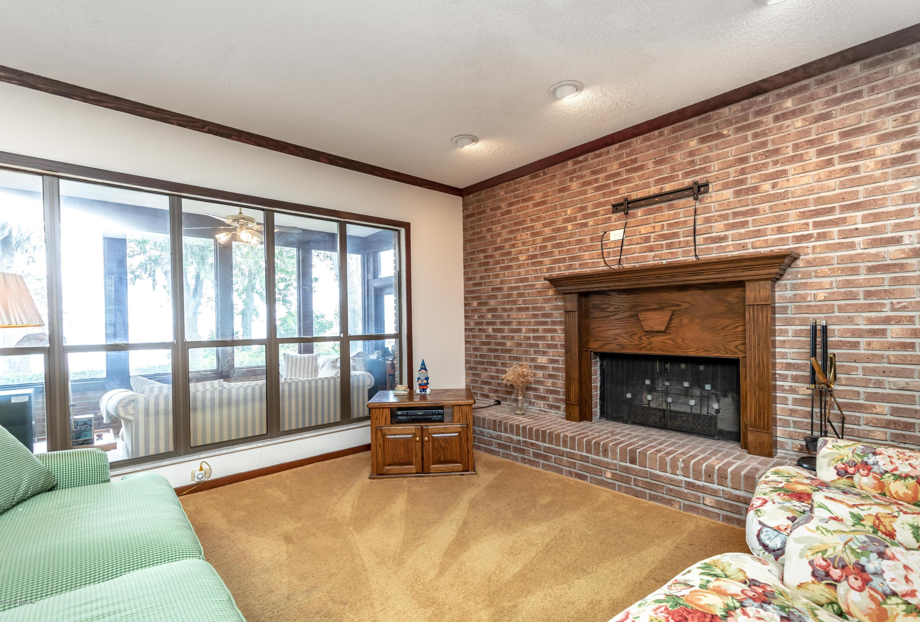 2911 Front Road Jacksonville, FL 32257 - Photo 40 of 71 a living room with a fireplace a rug and a floor to ceiling window