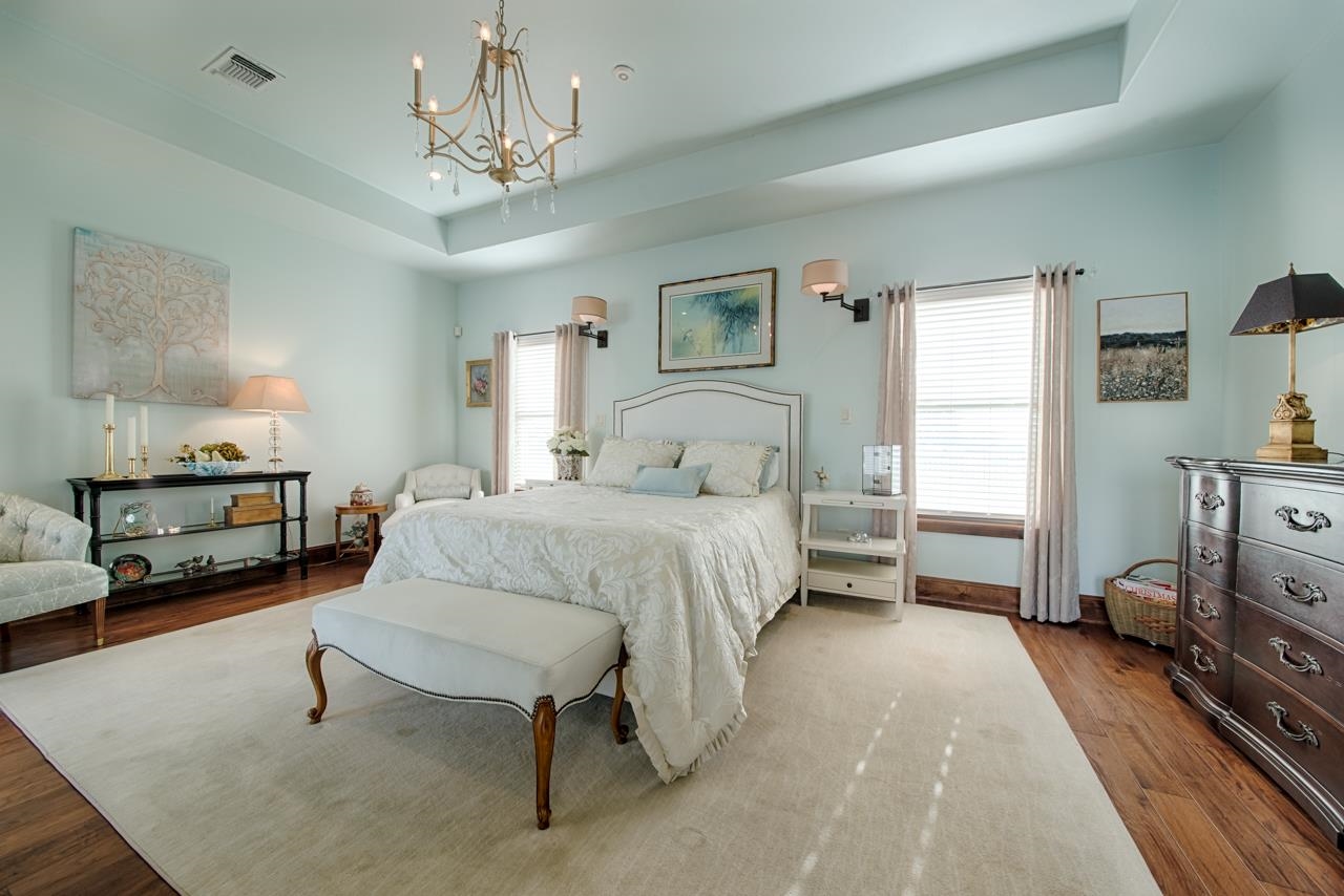 1600 Legends Parkway Kingsland, TX 78639 - Photo 11 of 30 a bedroom with a bed a chandelier and a dresser