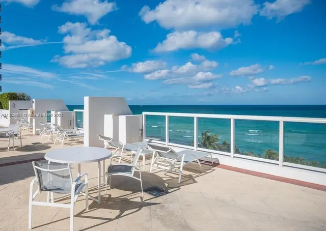 a view of a patio with dining table and chairs with floor to ceiling window