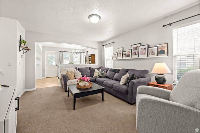 174 Rockey Park Lane, Unit 34 Draper, UT 84020 - Photo 4 of 20 Living room featuring arched walkways, a textured ceiling, light colored carpet, and a chandelier