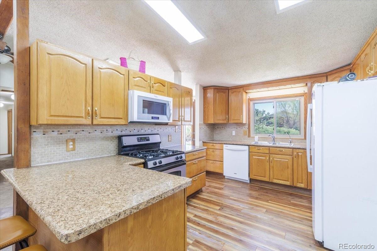2283 Haskell Way Watkins, CO 80137 - Photo 8 of 36 a kitchen with a stove a sink and a wooden cabinets