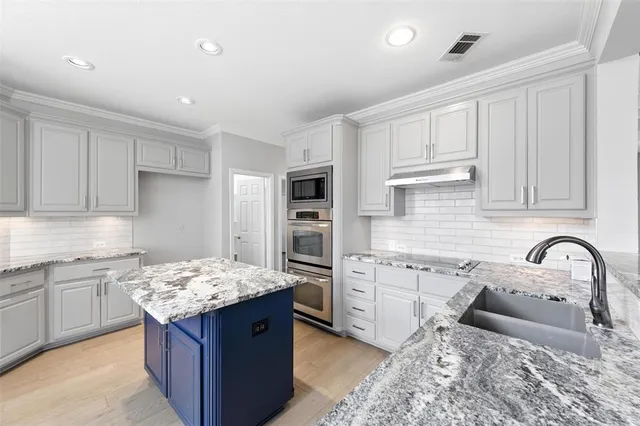 a kitchen with granite countertop a sink stove and refrigerator