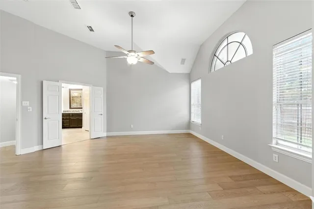 a view of an empty room with a window and wooden floor