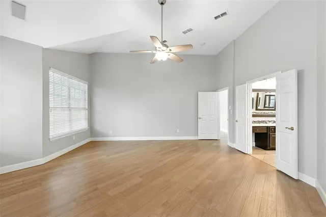 a view of an empty room with a window and wooden floor