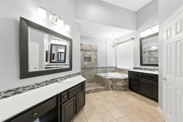 a spacious bathroom with a granite countertop double vanity sink a mirror and a bathtub