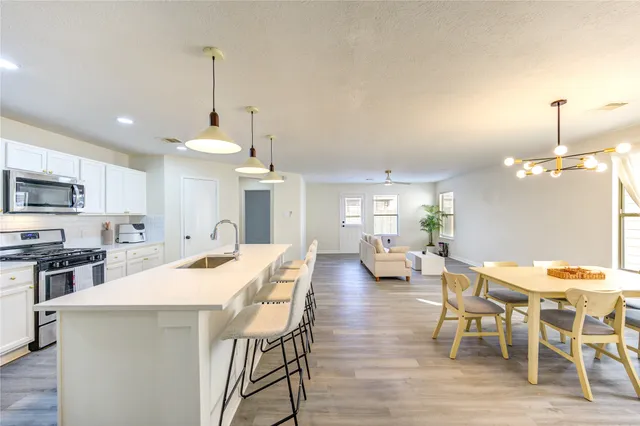 a view of a dining room and livingroom with furniture wooden floor a chandelier
