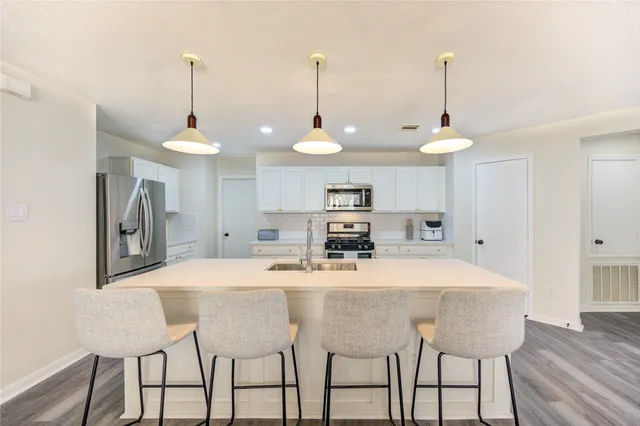 a kitchen with stainless steel appliances kitchen island granite countertop a table chairs and a refrigerator