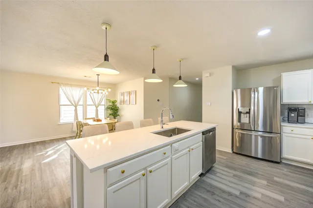 a large kitchen with stainless steel appliances kitchen island granite countertop a stove a sink dishwasher and a microwave oven with white cabinets