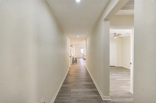 a view of a hallway with wooden floor and a bathroom