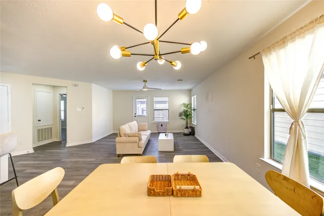 a living room with furniture kitchen view and a wooden floor