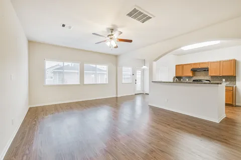 a view of an empty room with window and wooden floor