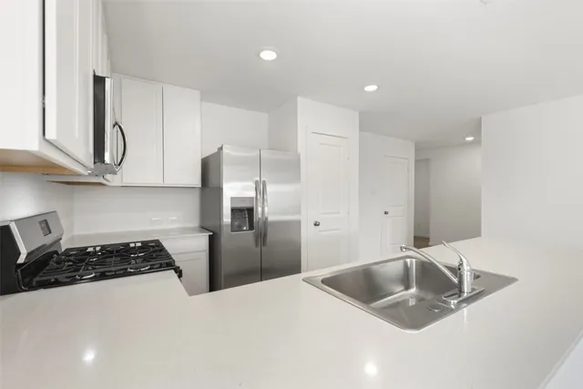 a kitchen with stainless steel appliances granite countertop a sink a refrigerator and a stove top oven