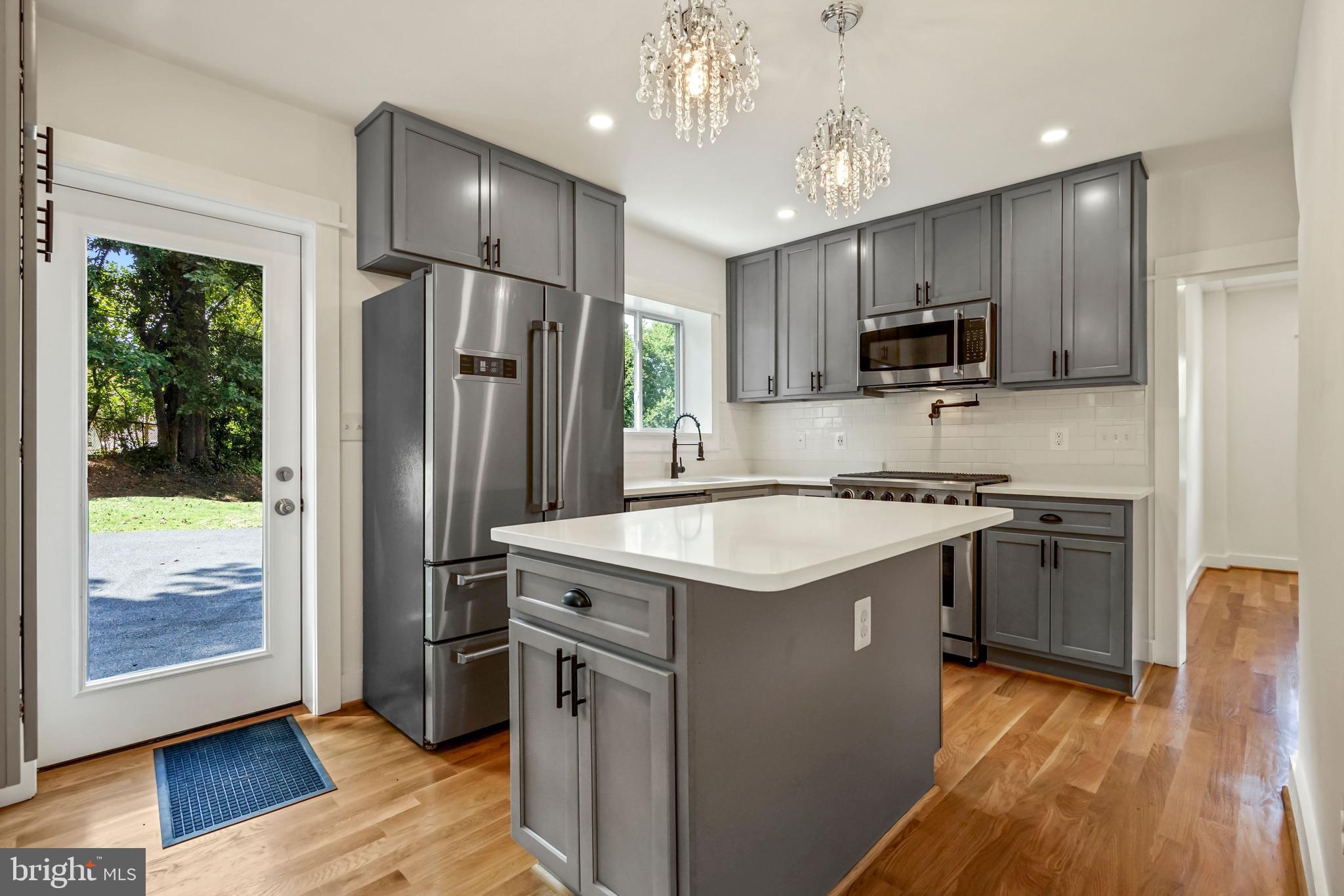 a kitchen with kitchen island granite countertop stainless steel appliances cabinets a sink and a wooden floor
