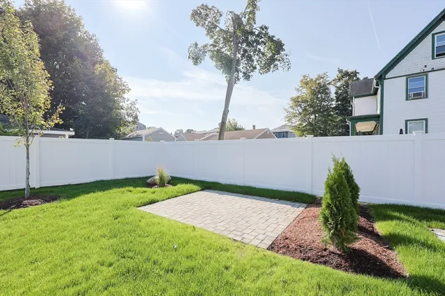 a view of backyard with plants and large trees