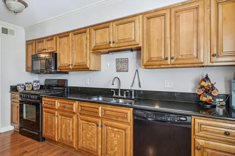 a kitchen with stainless steel appliances granite countertop a stove a sink dishwasher and cabinets with wooden floor