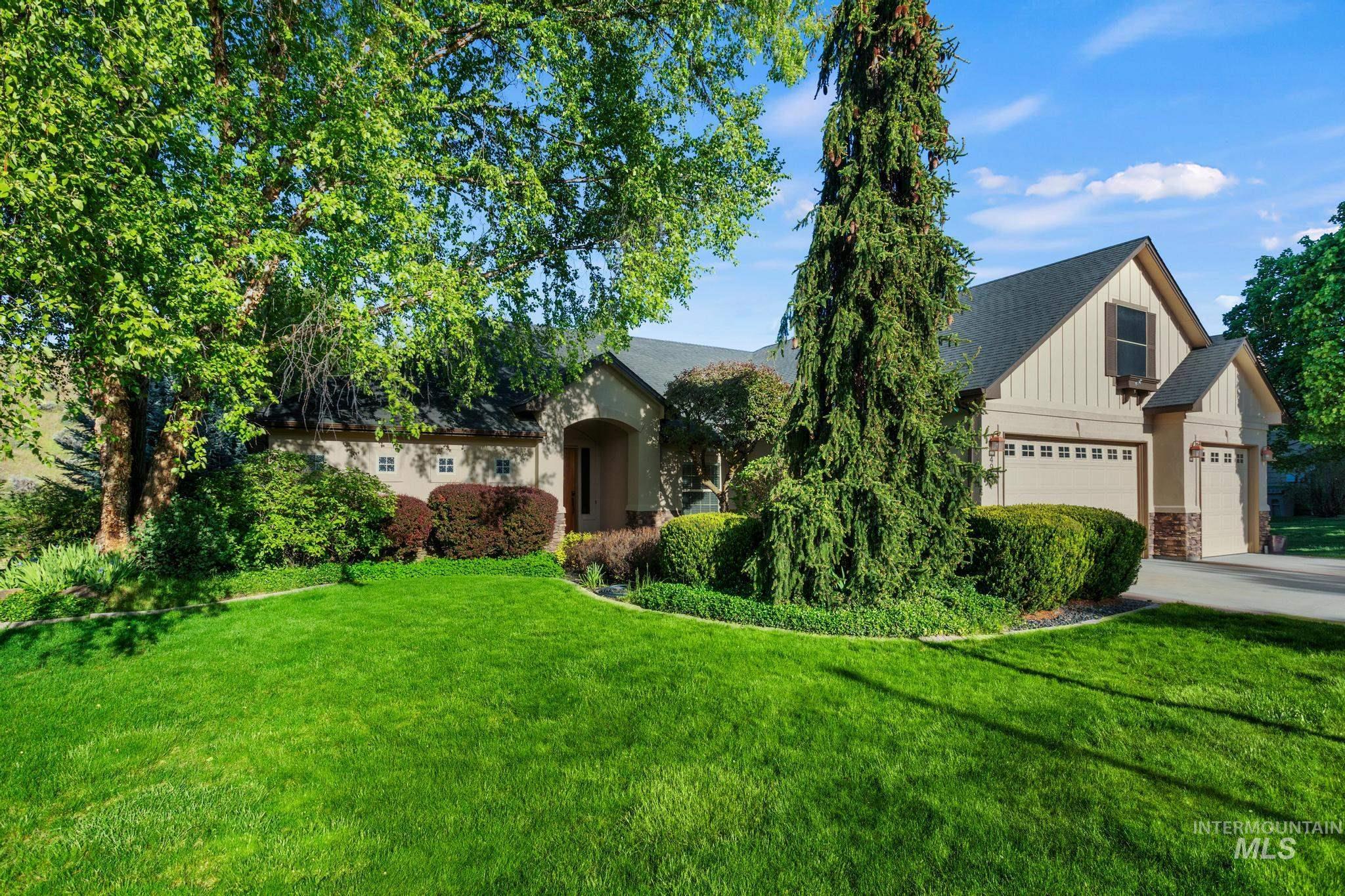 Craftsman-style exterior featuring a covered entry, board and batten siding, stone accents, a multi-car garage, and established landscaping