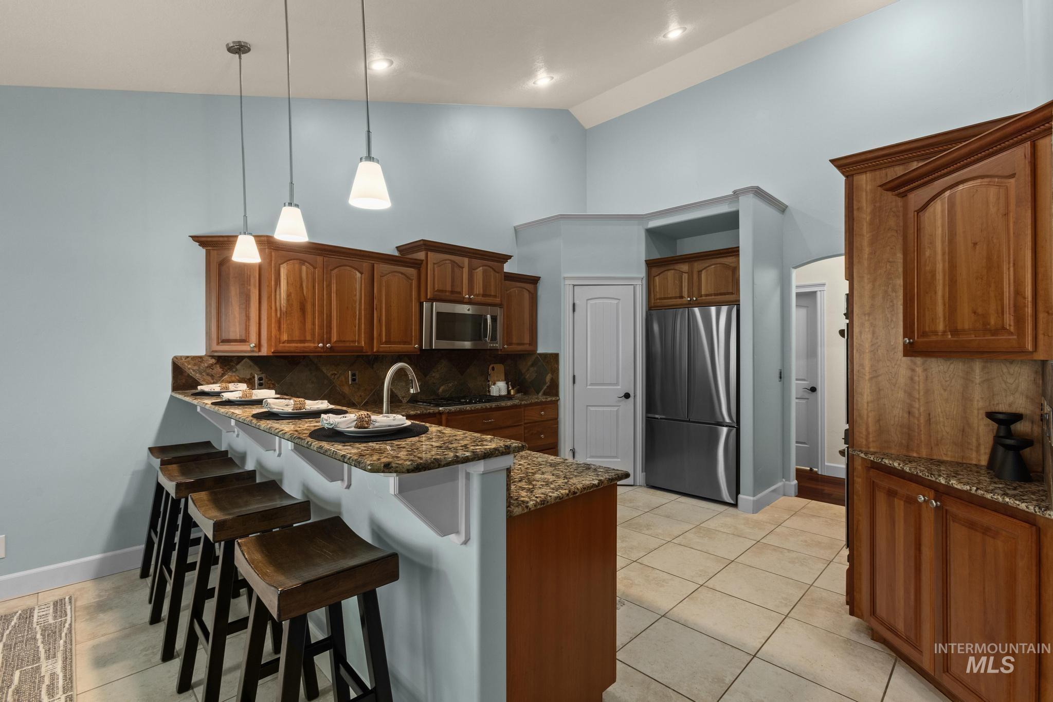 4946 North Villa Ridge Way Boise, ID 83703 - Photo 11 of 49 Kitchen featuring wood cabinetry, integrated stainless steel appliances, granite countertops, and tile flooring