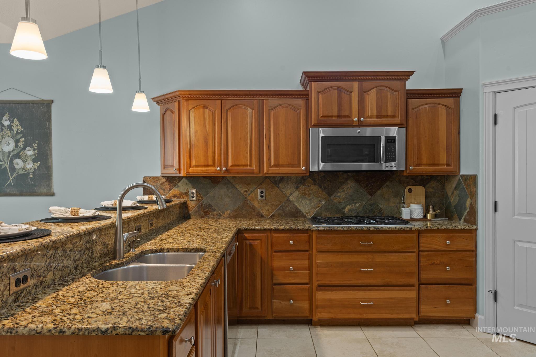 4946 North Villa Ridge Way Boise, ID 83703 - Photo 12 of 49 Kitchen featuring wood cabinetry, granite countertops, a double basin sink with a gooseneck faucet, a stainless steel microwave, and a gas range