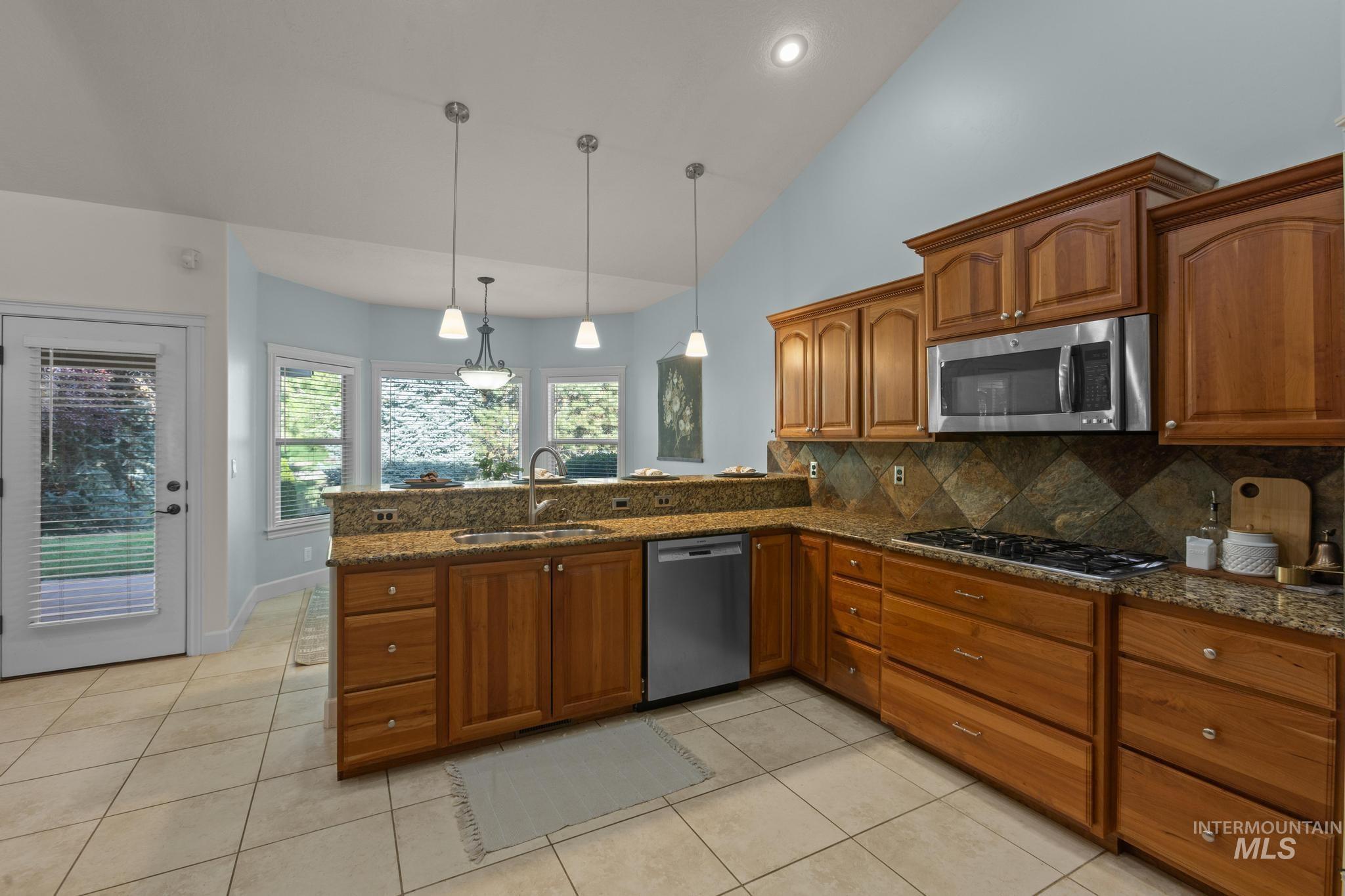 4946 North Villa Ridge Way Boise, ID 83703 - Photo 13 of 49 Kitchen featuring wood cabinetry, granite countertops, stainless steel appliances, and a tiled backsplash