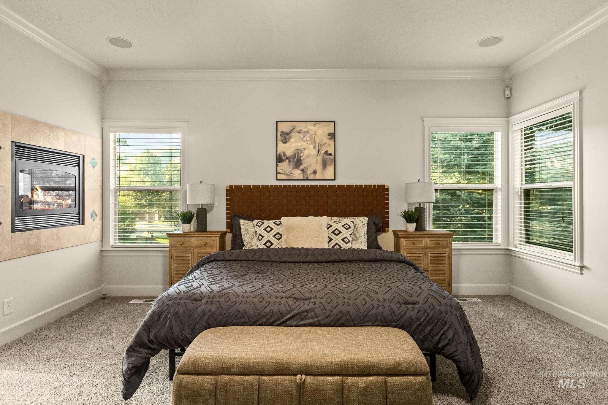 4946 North Villa Ridge Way Boise, ID 83703 - Photo 18 of 49 Carpeted bedroom featuring an integrated fireplace with a tiled surround, crown molding, and two windows with white trim