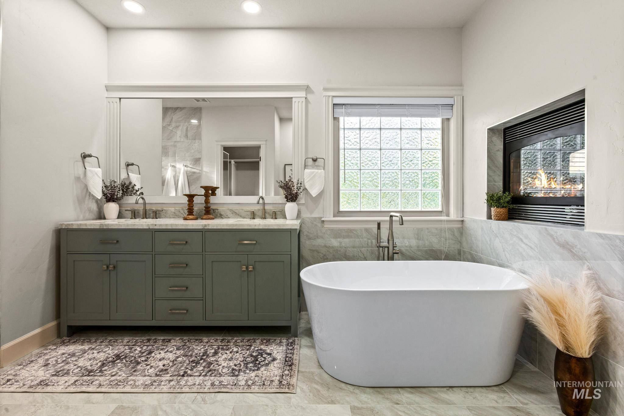 4946 North Villa Ridge Way Boise, ID 83703 - Photo 21 of 49 Freestanding soaking tub featuring a recessed fireplace, a dual vanity with a light-colored countertop, and a window with block glass