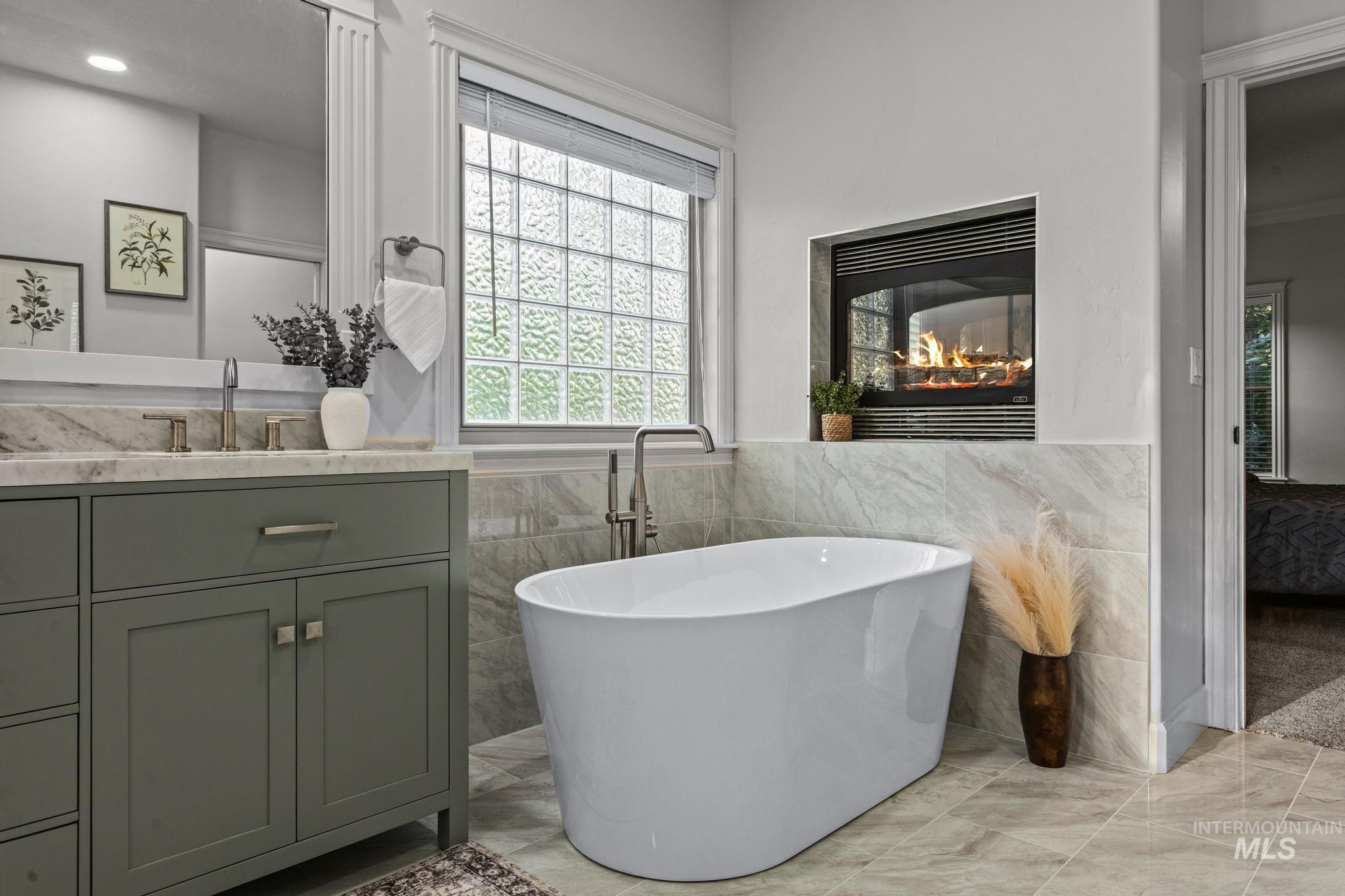 4946 North Villa Ridge Way Boise, ID 83703 - Photo 22 of 49 Freestanding soaking tub with a built-in fireplace feature, glass block window, and a vanity with a stone countertop and undermount sink